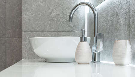 Modern bowl-shaped washbasin with chrome water mixer and soap dispenser in bathroom
