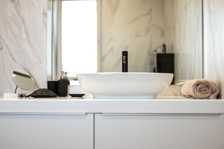 Modern washbasin with black faucet beside a stylish soap dispenser.の写真素材