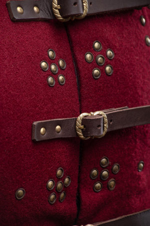Close-up of Red Brigandine Studded Details. Detailed view of leather strap with brass buckle and studded pattern on a medieval torso armor.の写真素材