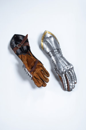 Pair of steel knight gauntlets with golden accents. Detailed metallic hand protection gloves, part of historical armor, lying side by side on a light uniform background.の写真素材