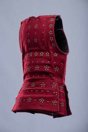 Red Medieval Brigandine with Studded Detail. Sleeveless torso armor featuring numerous studded embellishments and adjustable leather straps with brass buckles.の写真素材