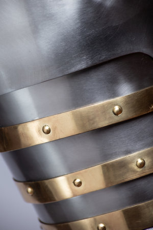 Close-Up Detail of Medieval Shoulder Armor. Textured surface of polished steel spaulders with decorative brass accents.の写真素材