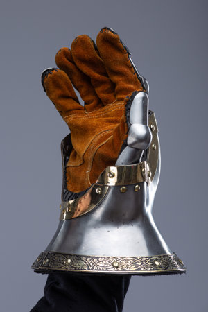 Silver Hourglass Gauntlets with Brass Details. This image shows a close-up of a pair of shiny silver hourglass gauntlets, featuring articulated fingers and brass accents along the edges and rivets.の写真素材
