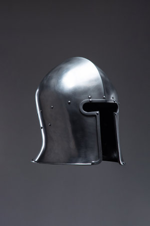 Silver Medieval Helmet with Open Face Guard. This image showcases a shiny silver helmet with an open face, featuring a rounded top and small rivets along the edges.の写真素材