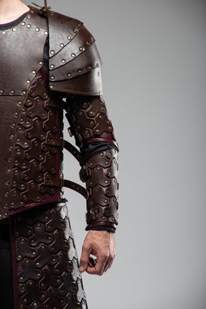 Brown Leather Arm Armor with Studded Design. This image shows a section of brown leather armor, likely for the arm, featuring a pattern of small studs and adjustable straps.の写真素材