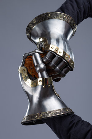 Pair of Silver Medieval Gauntlets with Decorative Brass Trim. This image shows a pair of shiny silver medieval gauntlets, featuring articulated fingers, decorative brass trim along the cuffs, and brown fabric lining visible inside.の写真素材