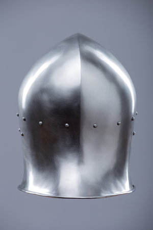 Silver Medieval Barbute Helmet with Brass Trim. This image shows a shiny silver helmet with a distinctive T-shaped opening for the face, accented with brass trim and rivets.の写真素材