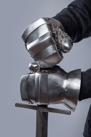 Pair of Silver Gauntlets Holding a Sword. This image shows a pair of shiny silver gauntlets, likely...