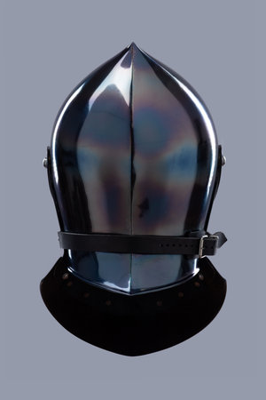 Dark Shiny Closed Helmet with Ventilation Holes. This image shows a dark, shiny helmet, possibly made of blackened steel, with a smooth, rounded shape and several small ventilation holes on the front.の写真素材