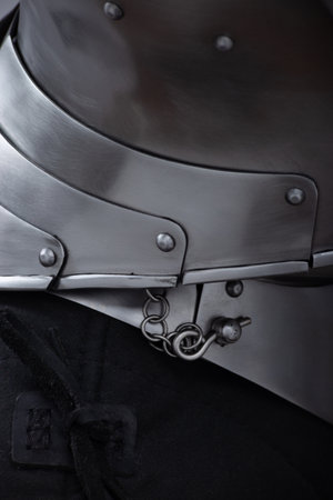 Close-up of medieval armor neck protection with chainmail. A detailed view shows layered metal plates forming neck armor, connected with small rivets and featuring a chainmail section attached with a ring and pin mechanism.の写真素材
