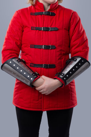 Red Quilted Gambeson with Black Leather Straps. This image shows a red quilted gambeson, a type of padded armor, with black leather straps and silver buckles down the front.の写真素材