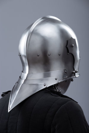 Medieval sallet helmet with visor and bevor. A shiny silver medieval sallet helmet features a hinged visor that can be raised and a bevor protecting the neck, all secured with small rivets.の写真素材
