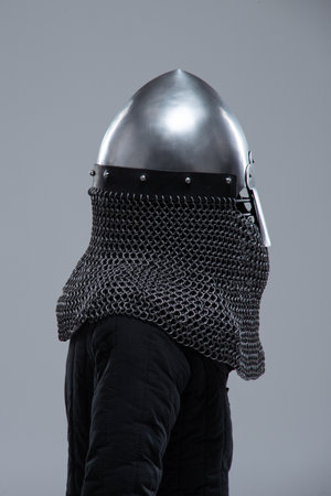 Silver Norman Helmet with Nasal Bar. This image shows a shiny silver Norman helmet, characterized by its conical shape and a prominent nasal bar extending down the front for facial protection. It also has a mail coif visible beneath.の写真素材