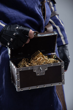Open Treasure Chest Overflowing with Gold. Close-up of a hand revealing a bounty of jewelry and coins.の写真素材