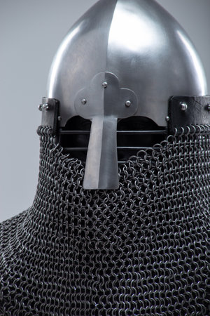 Silver Norman Helmet with Nasal Bar. This image shows a shiny silver Norman helmet, characterized by its conical shape and a prominent nasal bar extending down the front for facial protection. It also has a mail coif visible beneath.の写真素材