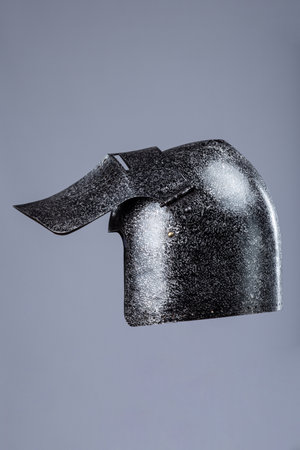Darkened Steel Medieval Helmet Cheek Piece. Side view of battle-worn head protection detail.の写真素材