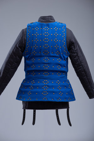 Bright Blue Brigandine Armor with Studs and Black Straps. This image shows a bright blue brigandine armor, featuring rows of small brass-colored studs and secured with multiple black leather straps and silver buckles.の写真素材