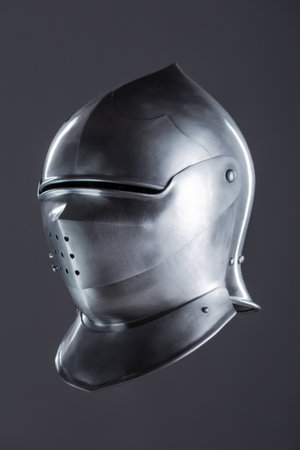 Polished Silver Medieval Armet Helmet with Perforated Visor. This shiny silver armet features a rounded skull, a protective bevor, and a visor with multiple small perforations.の写真素材