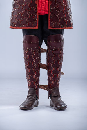 Close-up of Brown Leather Fantasy Leg Armor. Detailed view of the mannequin's leg armor featuring brown leather with red accents and multiple straps.の写真素材