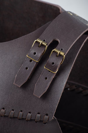 Close-up of Leather Straps and Rivets on Brown Cuirass. Detailed view of the fastenings on medieval torso armor.の写真素材