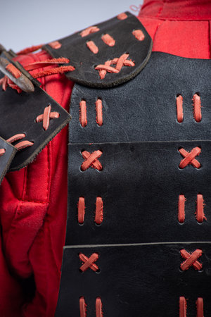 Close-up of Black and Red Leather Shoulder Armor. Detailed view of the mannequin's shoulder armor featuring black leather and contrasting red lacing.の写真素材