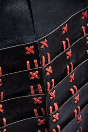 Close-up of Black and Red Leather Armor Lacing. Detailed view of the intricate red lacing connecting the black leather plates of the medieval cuirass.の写真素材