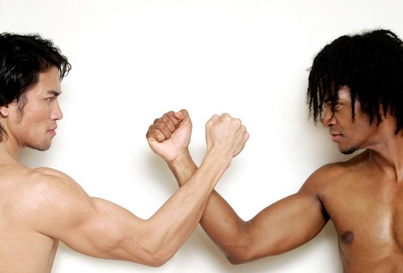 A shirtless muscular African American man and man arm wrestling