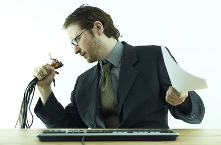 A bespectacled guy in business suit looking at the bundle of computer plugs