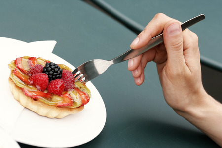 A hand holding a fork poking a fruit pie