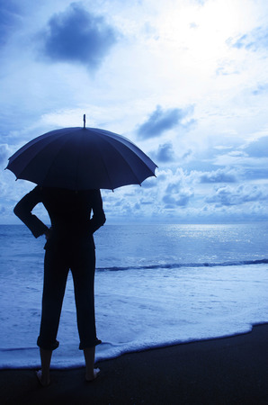 Businesswoman holding an umbrella on the beachの写真素材