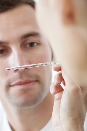 Doctor looking at thermometer in front of patient