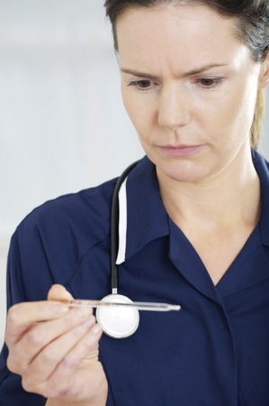 Female nurse looking at thermometer