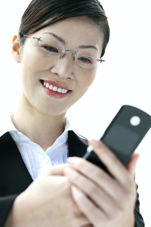 Businesswoman smiling while text messaging on the mobile phoneの写真素材