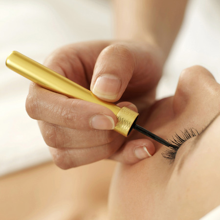 Hand applying liquid eyeliner on woman's eyelid