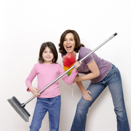 Mother and daughter with broom and feather dusterの写真素材