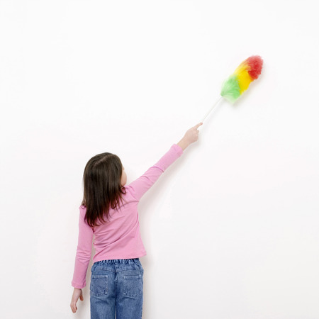 Girl dusting the wall with a feather duster