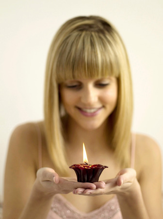 Pretty girl holding a lighted aromatherapy candleの写真素材