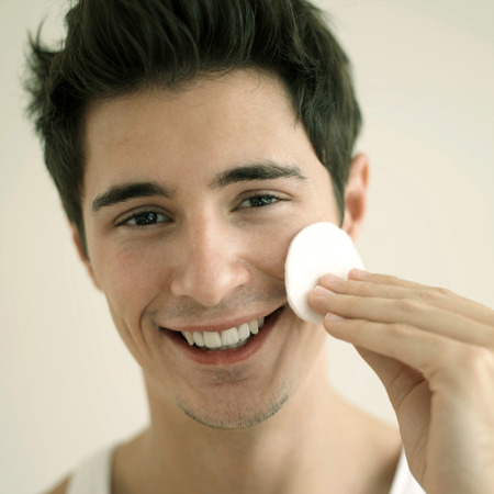 Man cleaning his face with cottonの写真素材