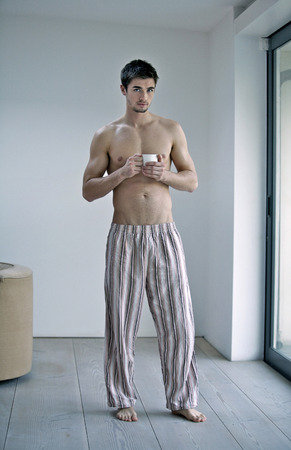 Man in pajamas holding a cup of coffeeの写真素材