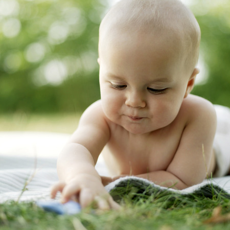 Baby boy lying forward in the park