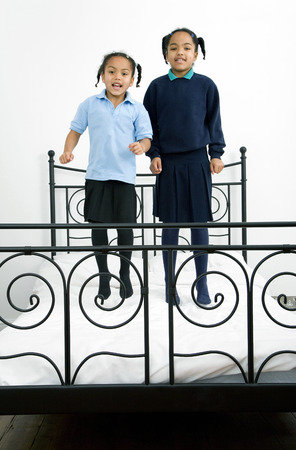 Two girls jumping on the bedの写真素材