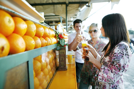 Couple enjoying fresh orange juice at beverage stallの写真素材