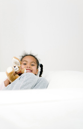Girl resting on the couch with her plush toyの写真素材