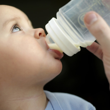 Baby boy drinking milk from baby bottle