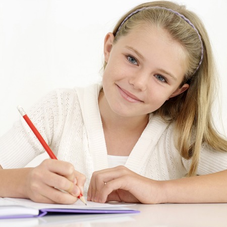 Girl smiling at the camera while writingの写真素材