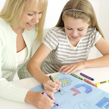Girl and woman colouring on a piece of cardboardの写真素材