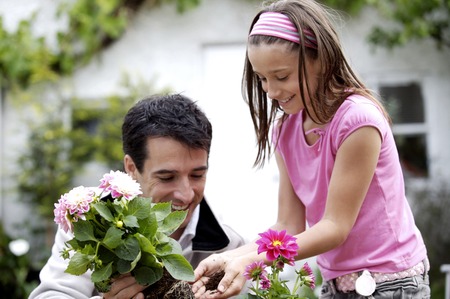 Man and girl planting flower into flower potの写真素材