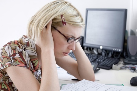 Woman looking stressed working at desk in a home officeの写真素材