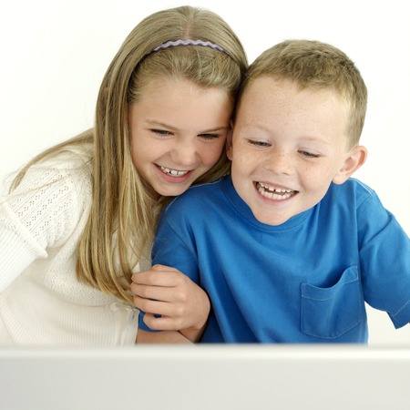 Boy and girl laughing while using laptop