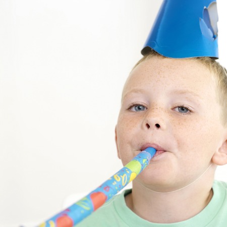 Boy in party hat blowing party horn blower